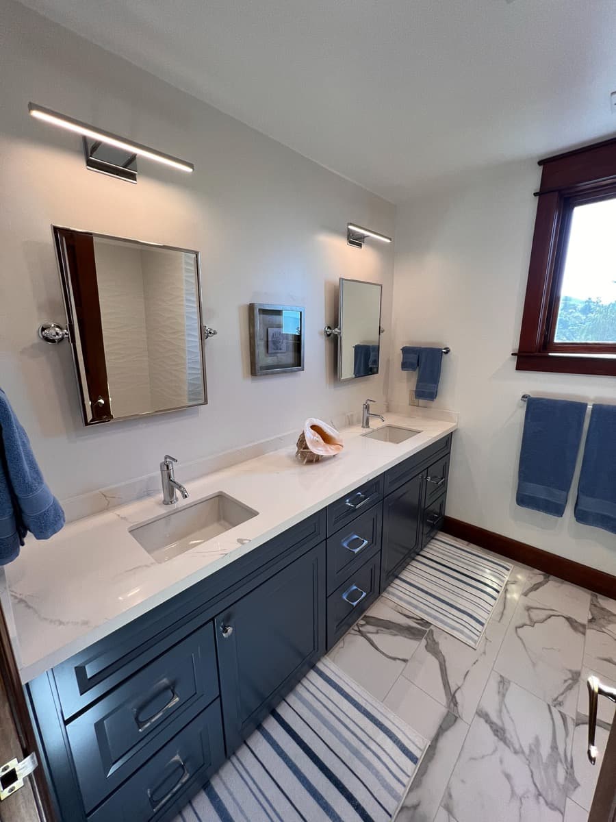 Navy shaker double vanity with polished chrome pulls and a white marble counter with two undermount sinks