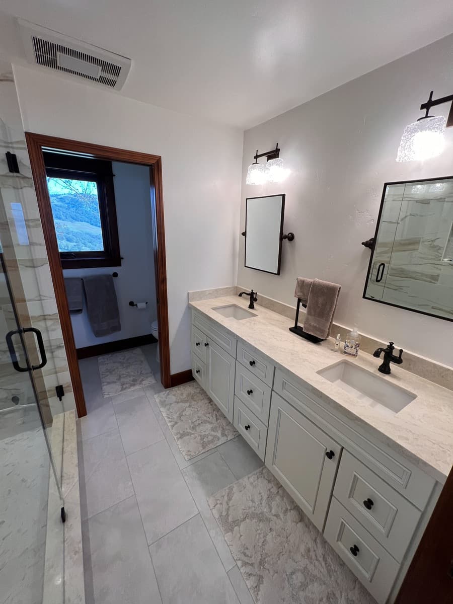 White shaker double vanity with beveled inset panels, oil-rubbed bronze pulls, and a marble top